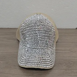 Vista detallada de una gorra de béisbol beige decorada con pedrería plateada.