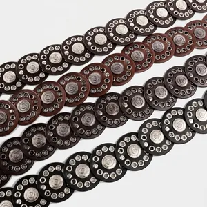 Close-up detail of Bohemian style leather belts with circular metal grommets and medallions