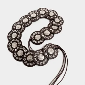 Detailed view of bohemian style belt with metallic eyelets and leather discs