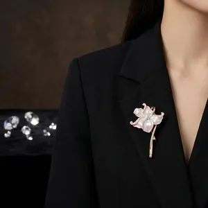 Gros plan d'une élégante broche de lys en émail rose sur un blazer noir classique