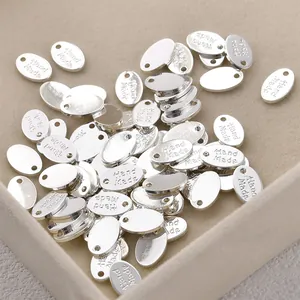 Detailed macro view of silver oval metal tags engraved with 'Hand Made' for DIY jewelry