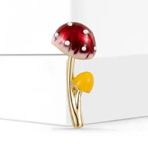 Makrodetail einer süßen rot-gelben Emaille-Pilzbrosche aus goldfarbener Legierung.