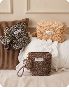 Detailed view of multiple plush leopard print cosmetic bags with fluffy pom-pom keychains and tags