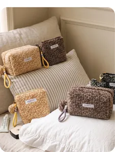 Macro view of multiple leopard print plush cosmetic bags on a bed
