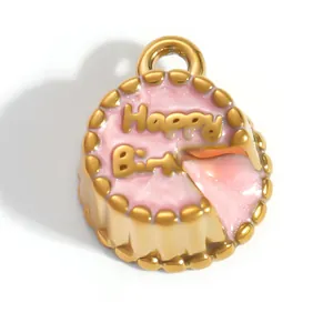 Macro view of gold-plated pink enameled cake charm with Happy Birthday design