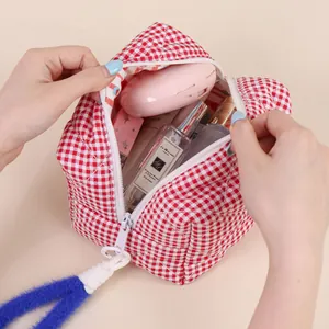 Trousse à maquillage matelassée à carreaux rouge et blanc avec grande tirette bleue.