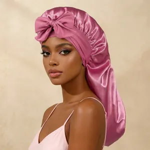 Détail d'un bonnet de nuit en satin rose avec un grand nœud pour les cheveux.