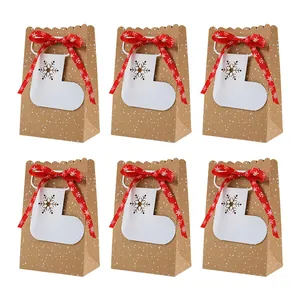 Set van zes kerst kraftpapier geschenktassen met rode linten en witte sneeuwvloklabels