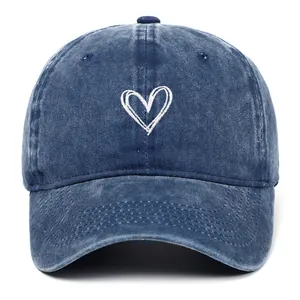Gedetailleerd vooraanzicht van wit geborduurd hart op een gewassen blauwe denim pet