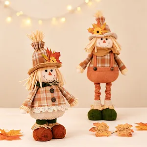 Pair of Harvest Festival scarecrow dolls with retractable legs and autumn leaf decorations