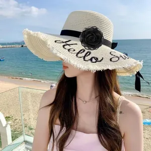 Vue détaillée d'un accessoire fleur de camélia noir fait main de 8 cm sur un chapeau d'été