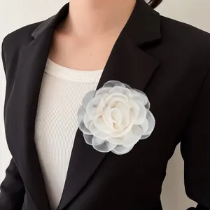 Détail d'une broche camélia de 8 cm en fil de cristal blanc faite main sur un blazer