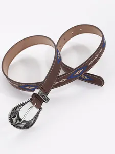 Close-up of bohemian brown leather belt with blue diamond embroidery and ornate silver buckle.