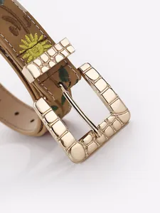 Detailed close-up of a vintage bohemian embroidered belt with a textured gold buckle