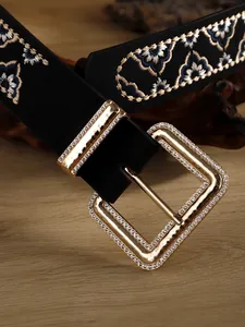Macro detail of bohemian black embroidered belt featuring a rhinestone gold buckle