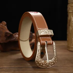 Detailed view of vintage gold floral buckle on bohemian embroidered brown leather belt