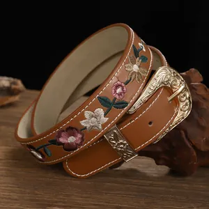 Detailed close-up of a brown vintage leather belt featuring intricate floral embroidery