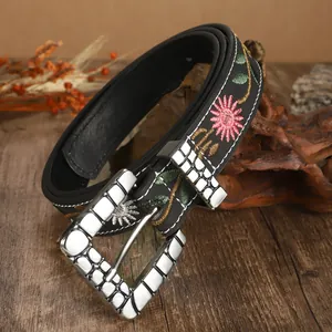 Close-up of bohemian black belt with floral embroidery and textured silver buckle.