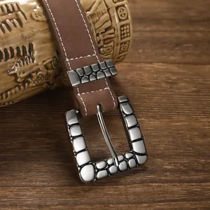 Close-up of a vintage silver buckle with a unique pebble texture on a brown leather belt.