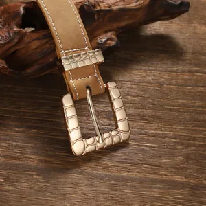Close-up of retro bohemian leather belt with textured gold square buckle.
