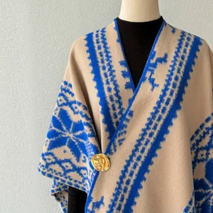 Nahaufnahme eines ethnischen Schals mit blauem geometrischem Muster und goldener Brosche