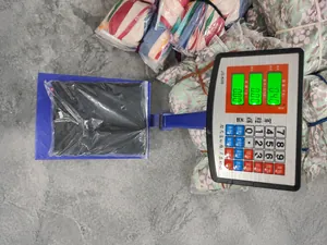 Close-up of a black jumpsuit package being weighed on a digital scale in a warehouse.