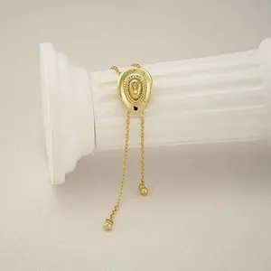 Detailed view of golden cowboy hat pendant necklace with textured brim on white pillar