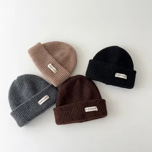 Detailed view of four colorful knitted winter beanies for babies with logo patches