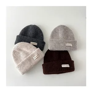 Detailed view of children's warm knit beanies in four neutral colors and ribbed texture