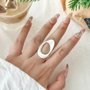 Close-up detail of a minimalist white geometric vortex open ring worn on a finger