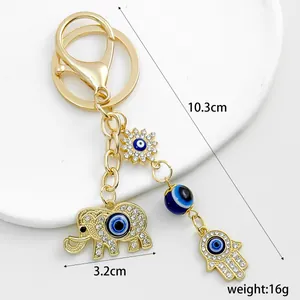 Detailed view of gold elephant and Hamsa hand keychain with blue evil eye charms