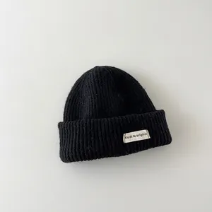 Detail showing the thick knit texture and branded label of a black winter beanie hat