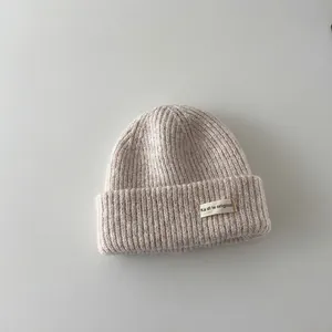 Close-up detail of a soft beige baby ribbed knit winter beanie with a stylish label