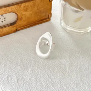Close-up view of a minimalist silver geometric open ring with a brushed matte finish