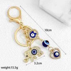 Detail view of a golden elephant and heart evil eye keychain with dimension markings