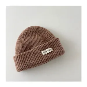 Detail view of brown knitted winter beanie for toddlers with decorative fabric patch