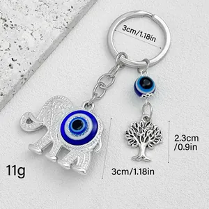 Close-up of silver elephant and tree of life evil eye keychain with measurements