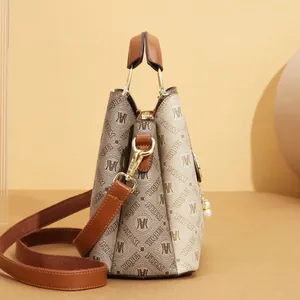Side view of luxury monogram printed tote bag with brown leather handles and gold hardware