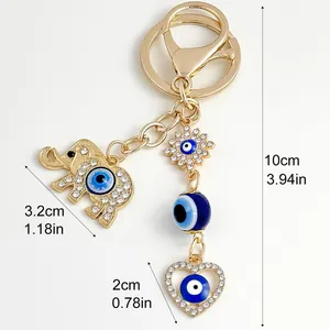 Detail view of a gold elephant evil eye keychain with dimensions in cm and inches