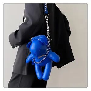Detailansicht einer leuchtend blauen Bären-Umhängetasche mit einer klobigen Silberkette.