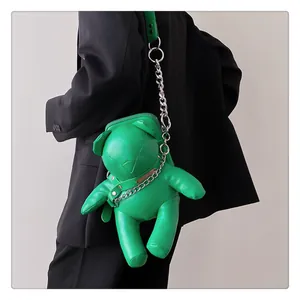 Detailansicht der grünen Teddybär-Tasche mit silberner Kette auf schwarzem Blazer