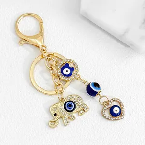Detailed macro view of a golden evil eye keychain featuring crystal elephant and heart charms