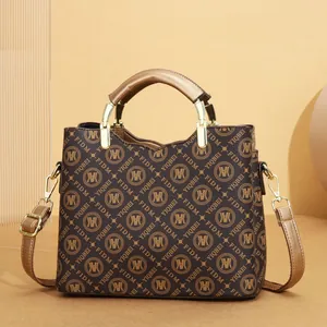 Close-up detail of a large capacity brown monogram tote bag featuring elegant gold handles