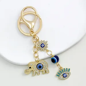 Close-up view of a golden keychain featuring decorative elephant and blue evil eye charms.