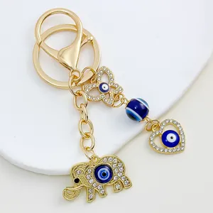 Close-up detail of golden keychain with rhinestone elephant and heart evil eye charms