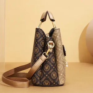 Side view of a brown monogram tote bag with gold-tone hardware and pearl detail