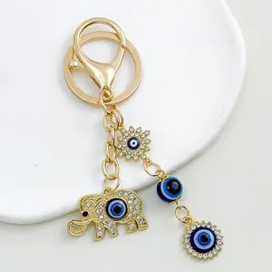 Detail shot of golden elephant keychain featuring blue evil eye charms and rhinestones