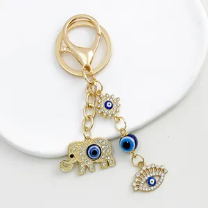 Exquisite close-up of a golden keychain featuring rhinestone elephant and blue evil eye charms