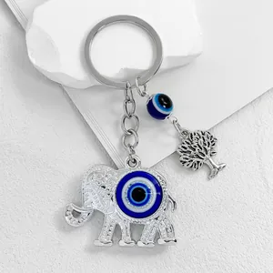 Detail shot of a silver elephant keychain with a blue evil eye bead and tree charm