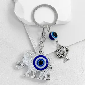 Detailed view of silver elephant keychain with evil eye bead and tree of life charm